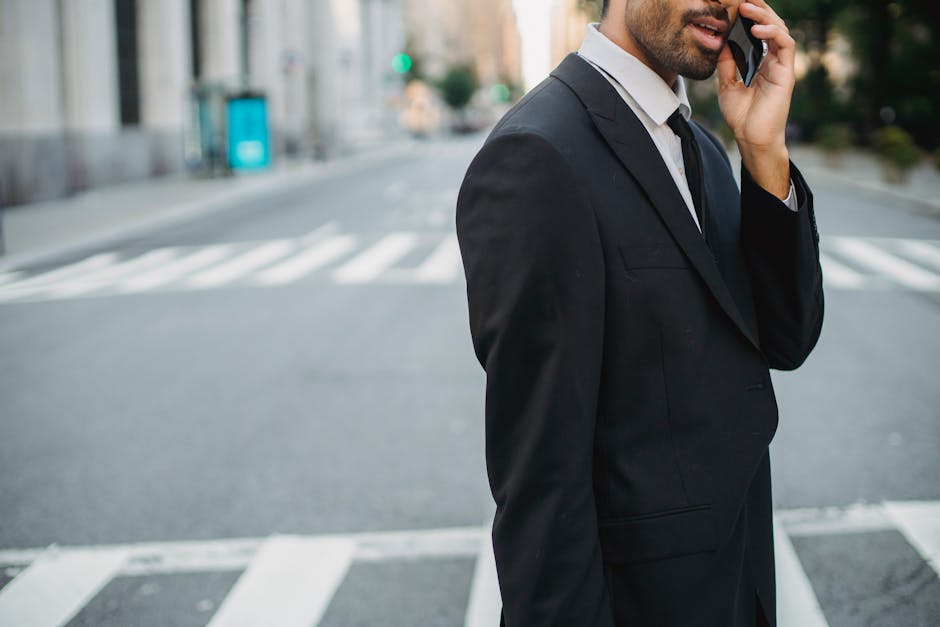 Young businessman talking on mobile phone in a city street wearing a black suit